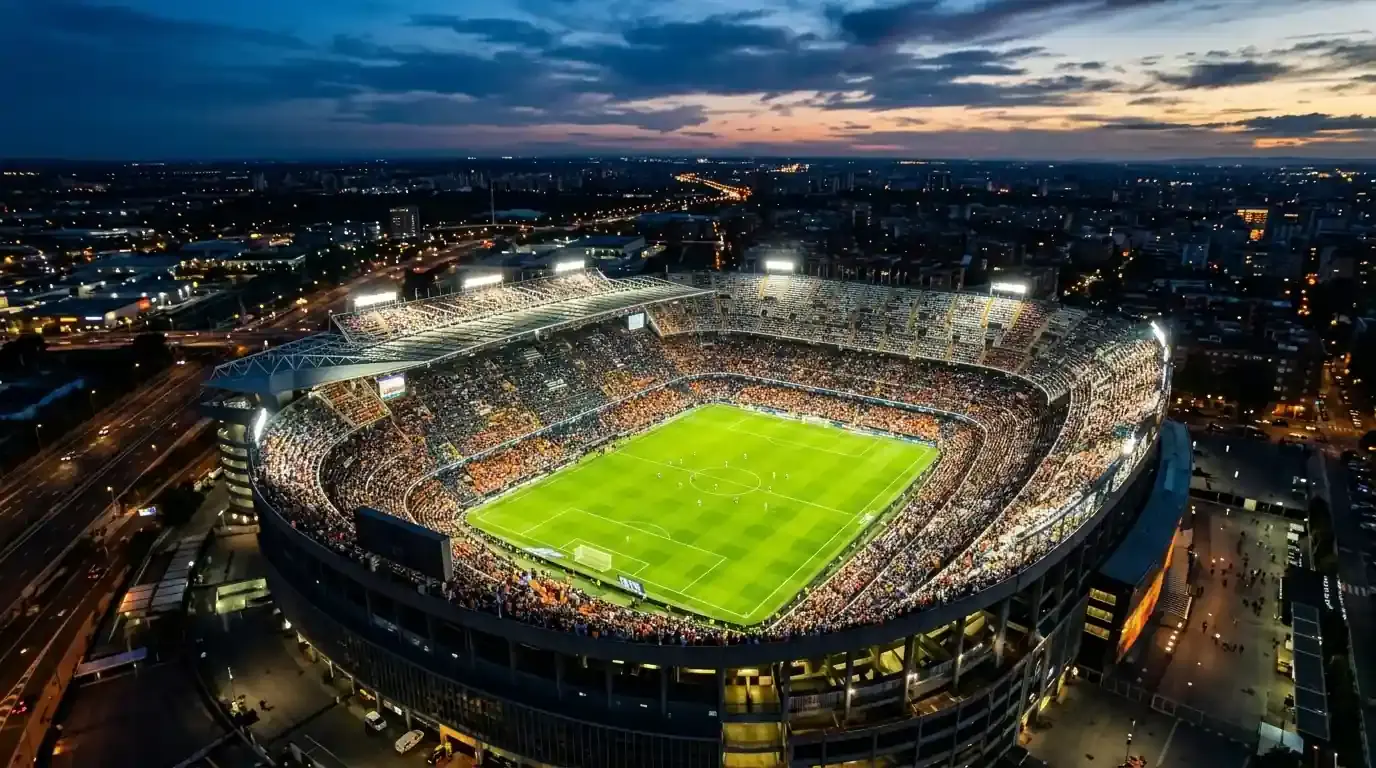 Vista aérea nocturna de un gran estadio de fútbol iluminado y lleno de aficionados antes de un partido del Mundial